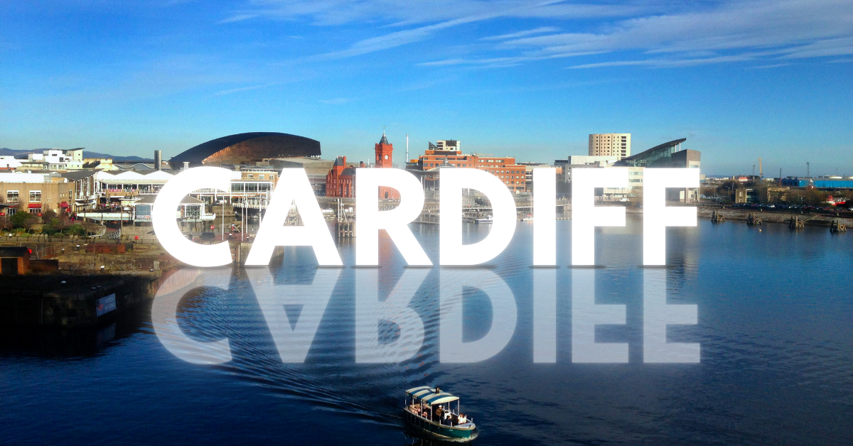 Cardiff skyline with prominent buildings and text reflection on water.